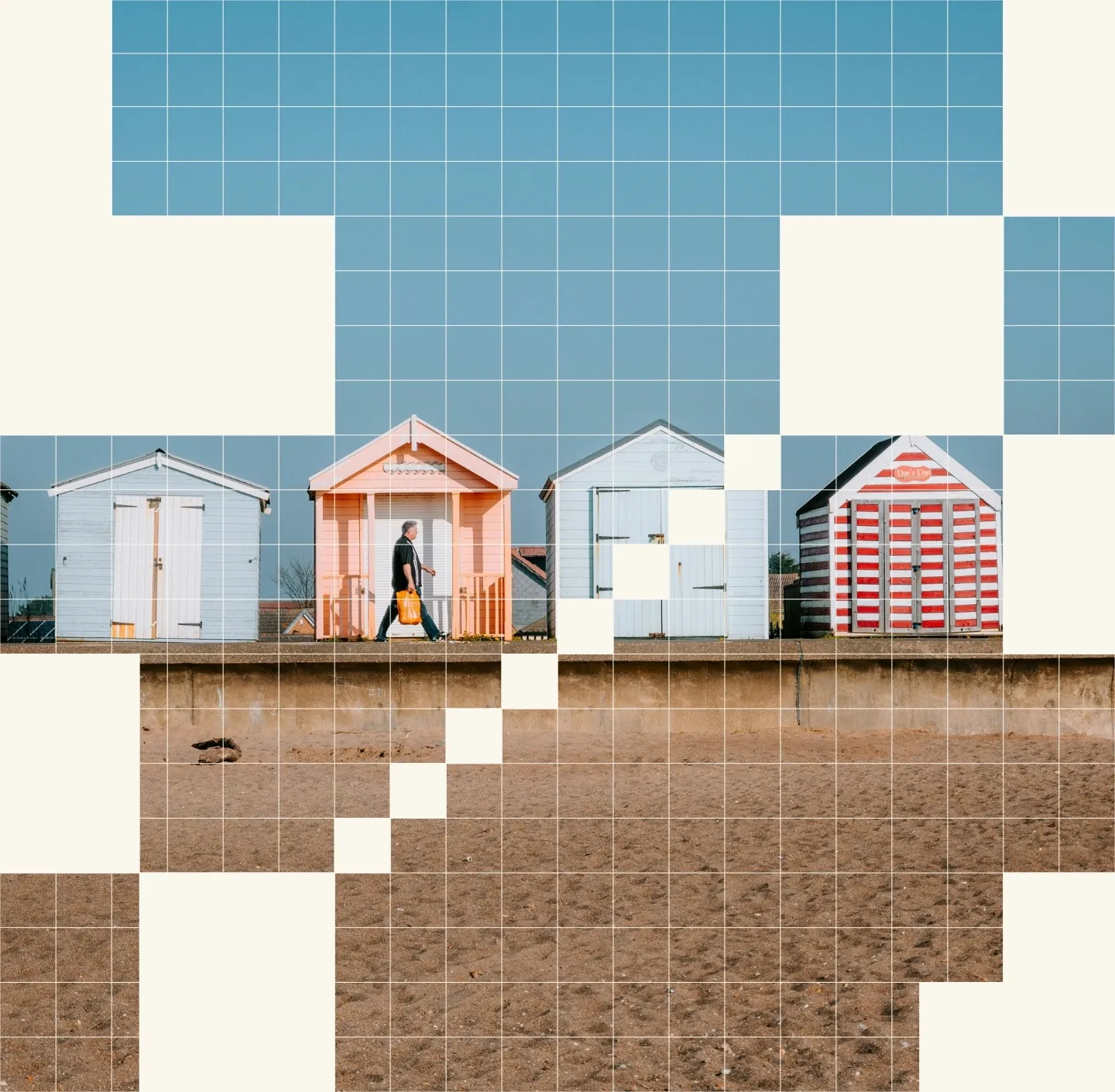 Image of a man holding a shopping back, walking in front of beach huts