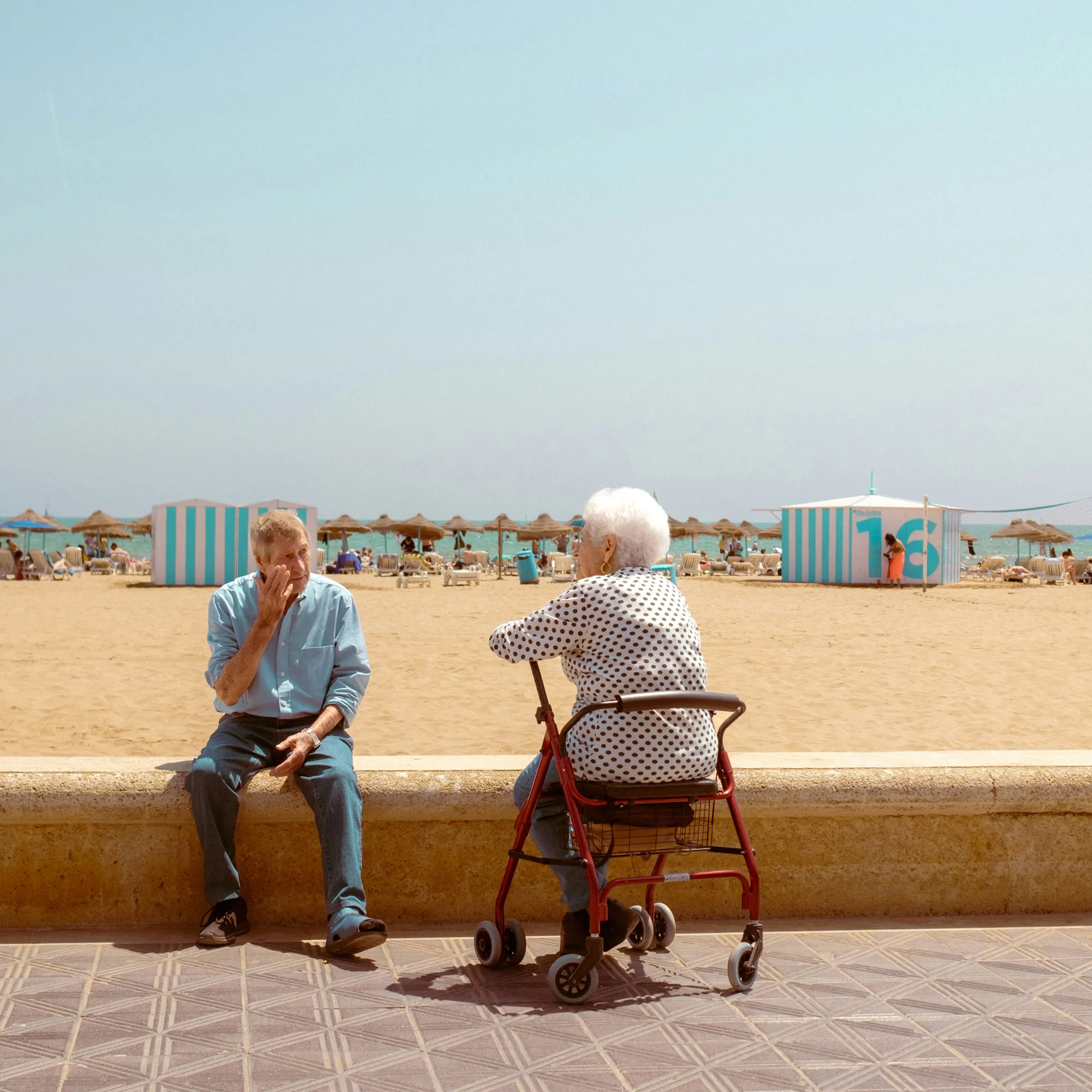 Two older people sitting by a beach