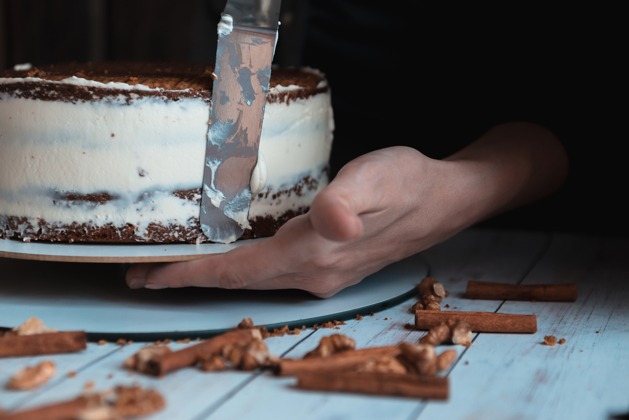 Close up of cook smearing butter cream on chocolate cake.